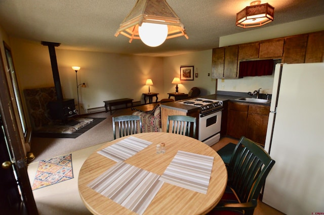 dining area with a wood stove, sink, light colored carpet, and a textured ceiling