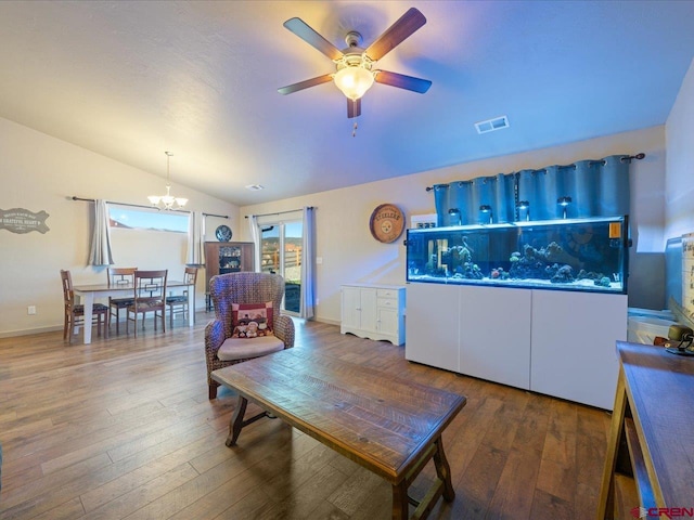 living room featuring hardwood / wood-style flooring, ceiling fan with notable chandelier, and vaulted ceiling