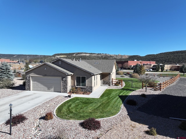 single story home featuring a mountain view, a garage, and a front lawn