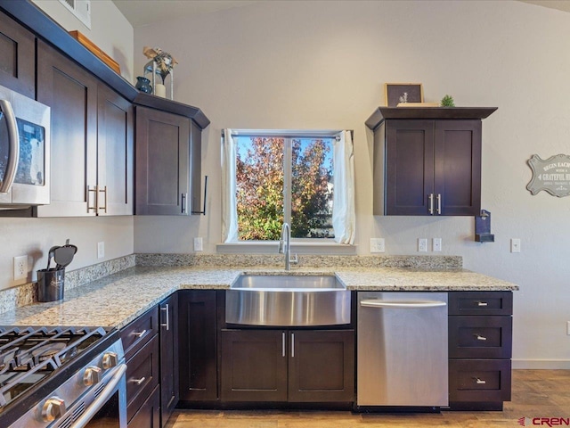 kitchen with dark brown cabinetry, lofted ceiling, sink, and appliances with stainless steel finishes