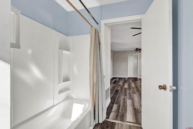 bathroom with washtub / shower combination, wood-type flooring, and ceiling fan