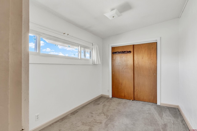 unfurnished bedroom featuring light carpet and a closet