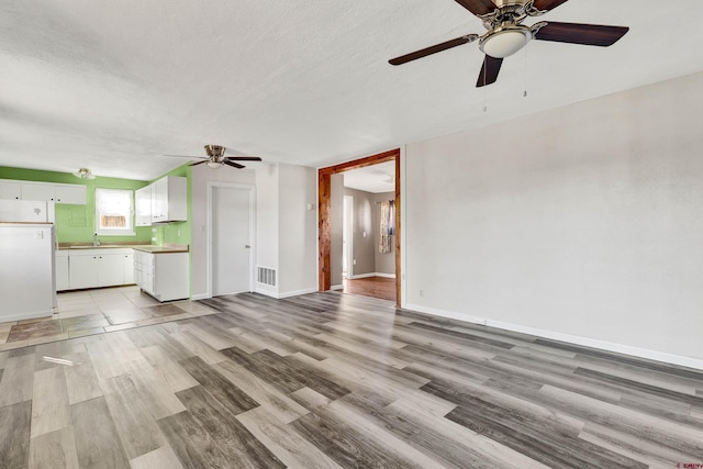 unfurnished living room featuring a textured ceiling, light hardwood / wood-style floors, and sink