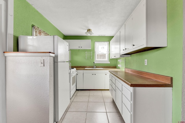 kitchen with white appliances, white cabinets, sink, a textured ceiling, and light tile patterned flooring