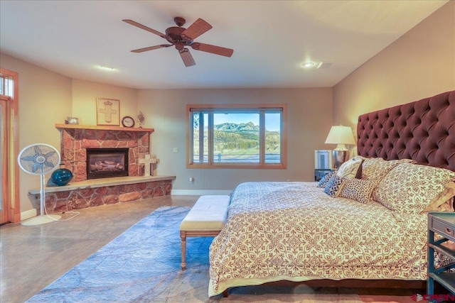 bedroom with ceiling fan and a stone fireplace