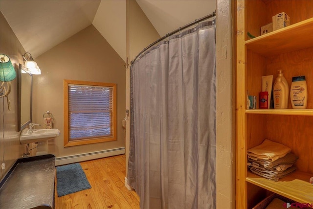 bathroom featuring sink, wood-type flooring, baseboard heating, and vaulted ceiling