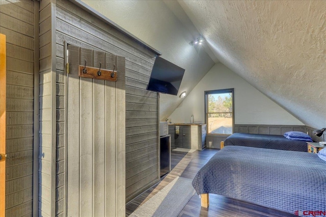 bedroom featuring hardwood / wood-style floors, lofted ceiling, and a textured ceiling