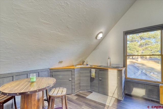 dining room featuring a textured ceiling, dark hardwood / wood-style flooring, lofted ceiling, and sink