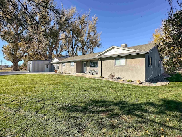 single story home with a garage, an outbuilding, and a front lawn