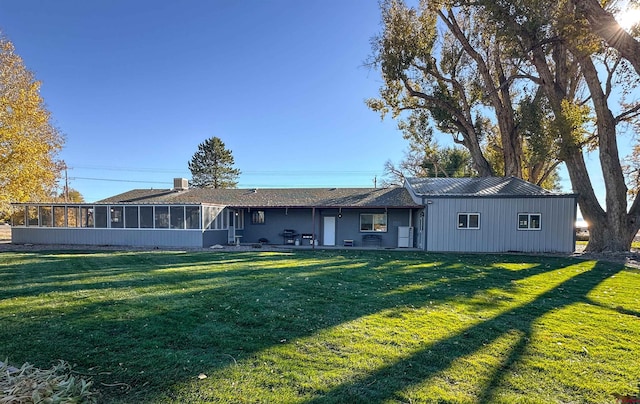 rear view of house featuring a sunroom and a yard