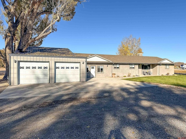 ranch-style home featuring solar panels, a front yard, and a garage