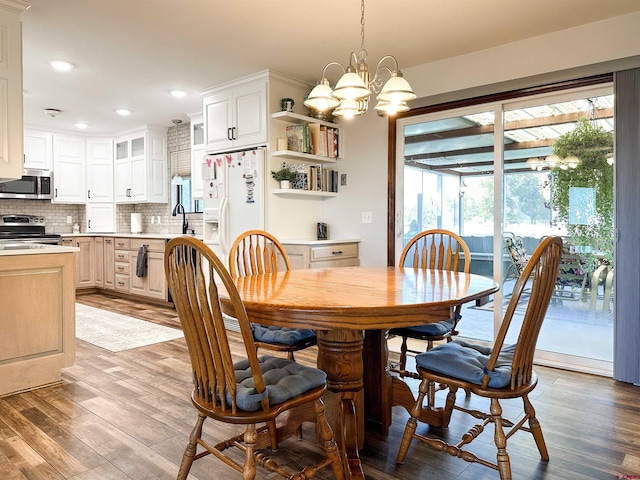 dining room with sink, light hardwood / wood-style flooring, and an inviting chandelier