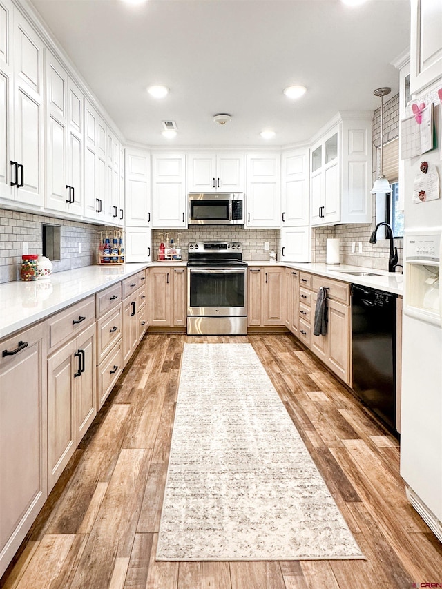 kitchen with white cabinetry, decorative light fixtures, decorative backsplash, appliances with stainless steel finishes, and light wood-type flooring