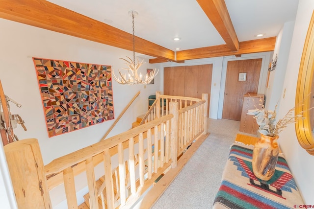 hall featuring beam ceiling, light colored carpet, and a chandelier