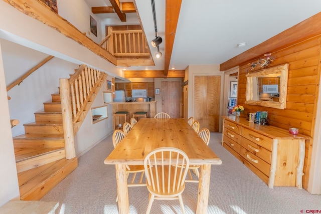 carpeted dining space with beamed ceiling