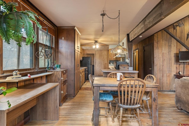 dining space featuring light wood-type flooring, ceiling fan, and wood walls