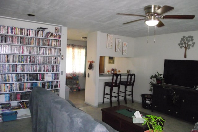 living room featuring ceiling fan and a textured ceiling