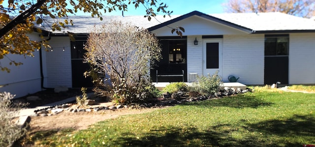 view of front of home with a sunroom and a front lawn