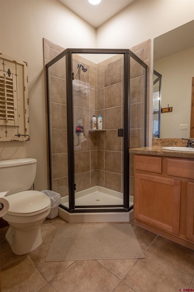 bathroom featuring vanity, tile patterned flooring, a shower with shower door, and toilet