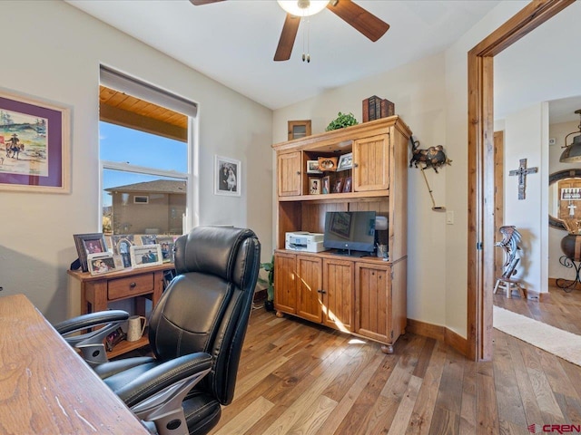 home office with light hardwood / wood-style floors and ceiling fan