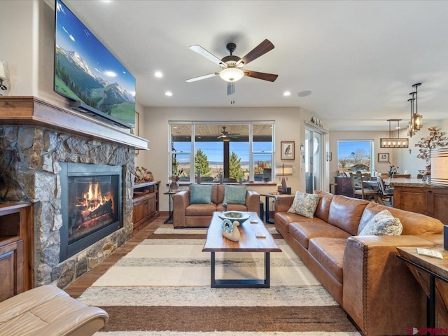 living room with ceiling fan, light wood-type flooring, and a fireplace