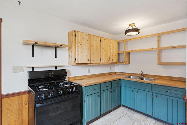 kitchen featuring wood counters, wood walls, sink, blue cabinetry, and black gas range oven