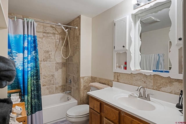 full bathroom with shower / bath combo with shower curtain, vanity, tile walls, and toilet