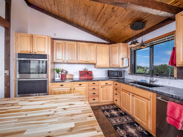 kitchen with lofted ceiling, sink, appliances with stainless steel finishes, decorative light fixtures, and butcher block counters