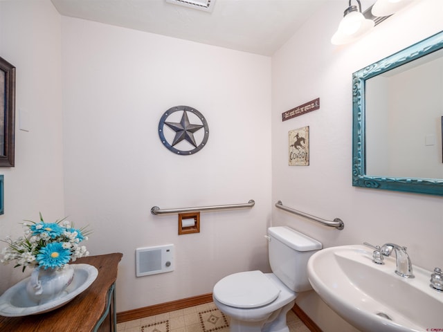 bathroom featuring toilet, sink, and heating unit