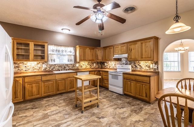 kitchen with tasteful backsplash, ceiling fan with notable chandelier, white appliances, sink, and hanging light fixtures