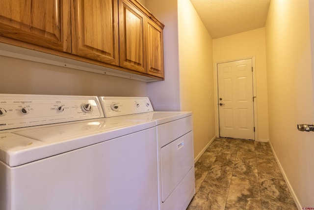 laundry room featuring washer and dryer, cabinets, and a textured ceiling