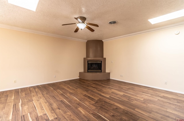 unfurnished living room with ceiling fan, a large fireplace, dark hardwood / wood-style floors, crown molding, and a textured ceiling