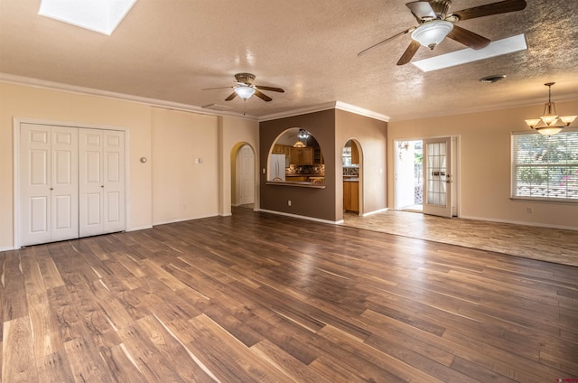 unfurnished living room featuring dark hardwood / wood-style floors, a skylight, and crown molding