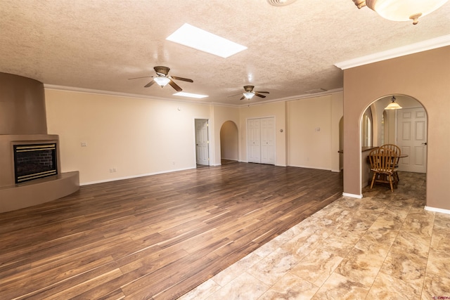 unfurnished living room with crown molding, hardwood / wood-style floors, ceiling fan, and a textured ceiling