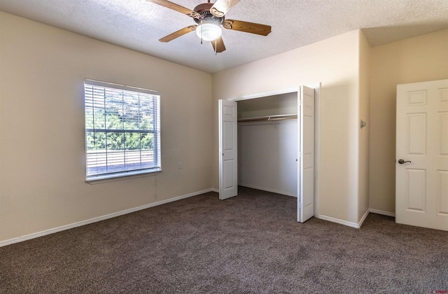 unfurnished bedroom featuring dark colored carpet, a textured ceiling, a closet, and ceiling fan