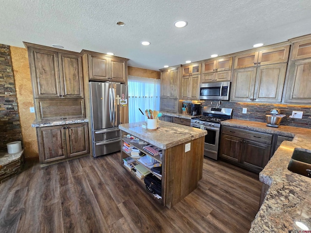 kitchen featuring light stone countertops, appliances with stainless steel finishes, dark hardwood / wood-style flooring, and a kitchen island