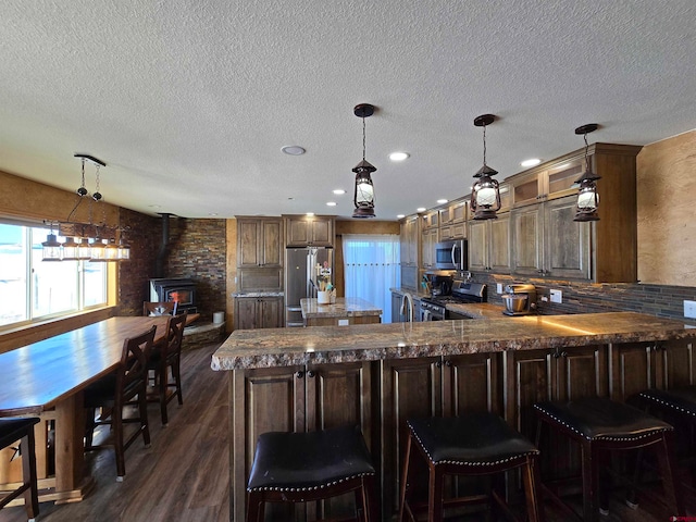 kitchen with dark hardwood / wood-style floors, a wood stove, a textured ceiling, and appliances with stainless steel finishes