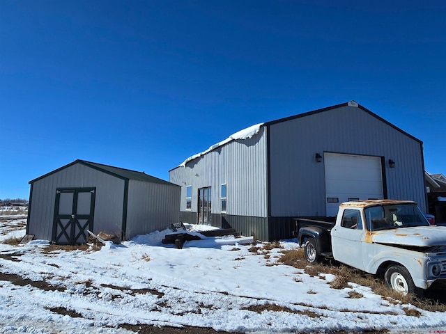 snow covered structure featuring a garage