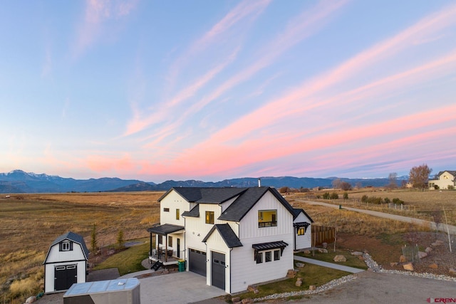 view of front of house with a mountain view, a garage, and a storage shed