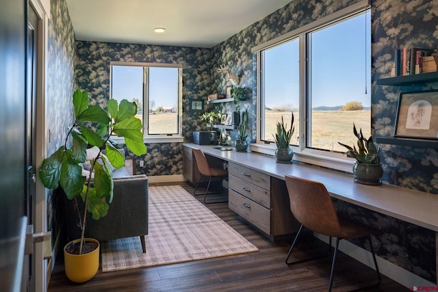 office with built in desk and dark wood-type flooring