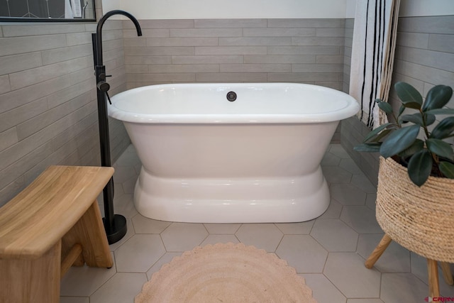 bathroom featuring tile patterned floors, a washtub, and tile walls