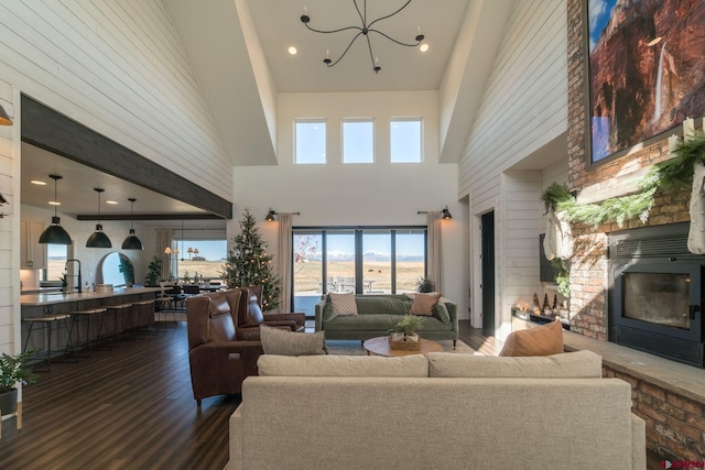 living room with a high ceiling, dark hardwood / wood-style flooring, a notable chandelier, and sink