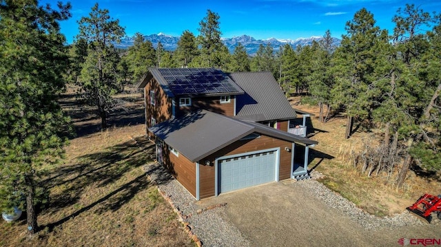 view of front facade with solar panels, a garage, and a mountain view