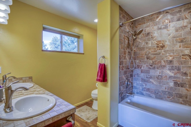 full bathroom featuring hardwood / wood-style flooring, vanity, toilet, and tiled shower / bath