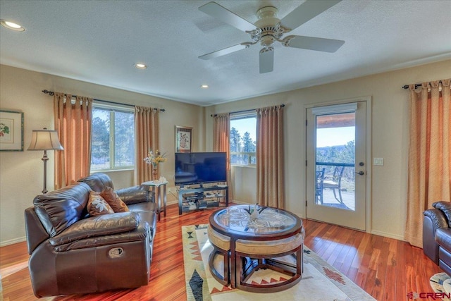 living room featuring ceiling fan, wood-type flooring, a textured ceiling, and a wealth of natural light