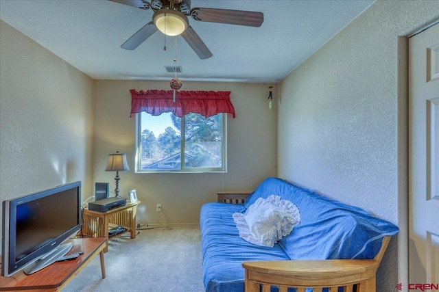 living area featuring ceiling fan, carpet, and a textured ceiling