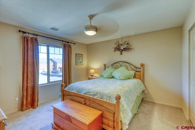 carpeted bedroom with ceiling fan and a textured ceiling