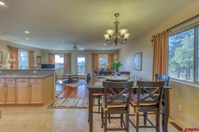 dining area featuring a textured ceiling, ceiling fan with notable chandelier, and light hardwood / wood-style flooring