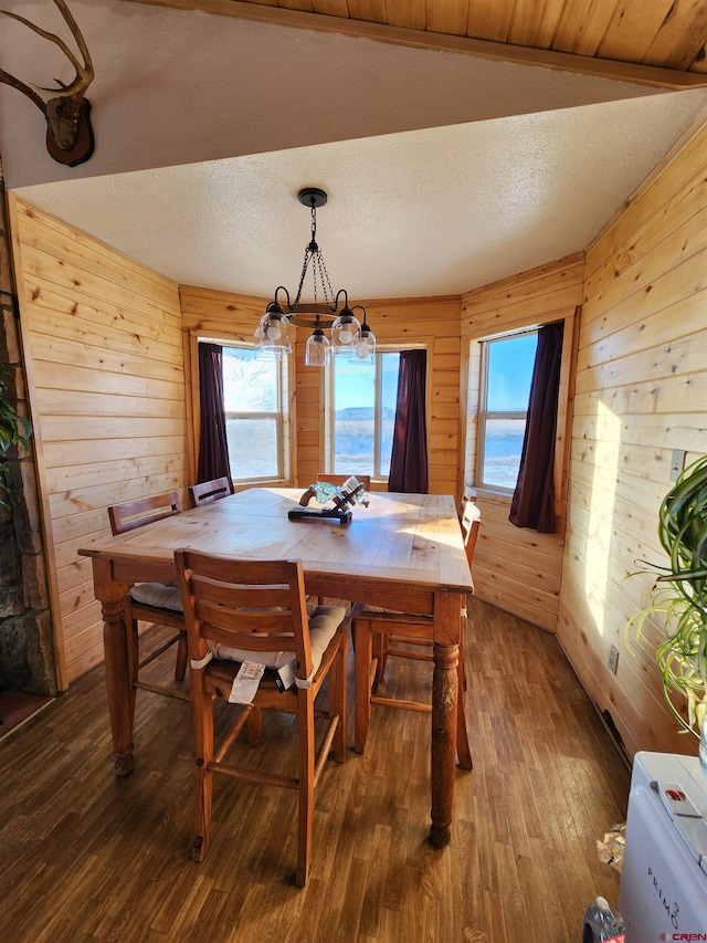 dining space featuring hardwood / wood-style floors, a notable chandelier, wood walls, and a textured ceiling