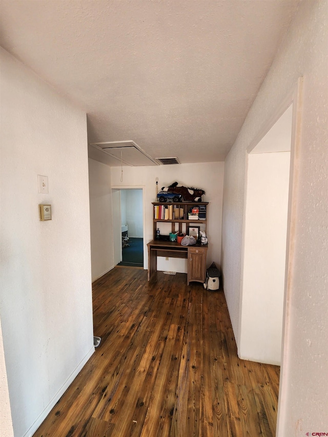 corridor with dark hardwood / wood-style floors and a textured ceiling